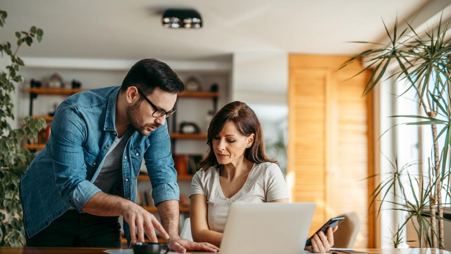 A man and a woman looking at online travel agencies on a laptop.