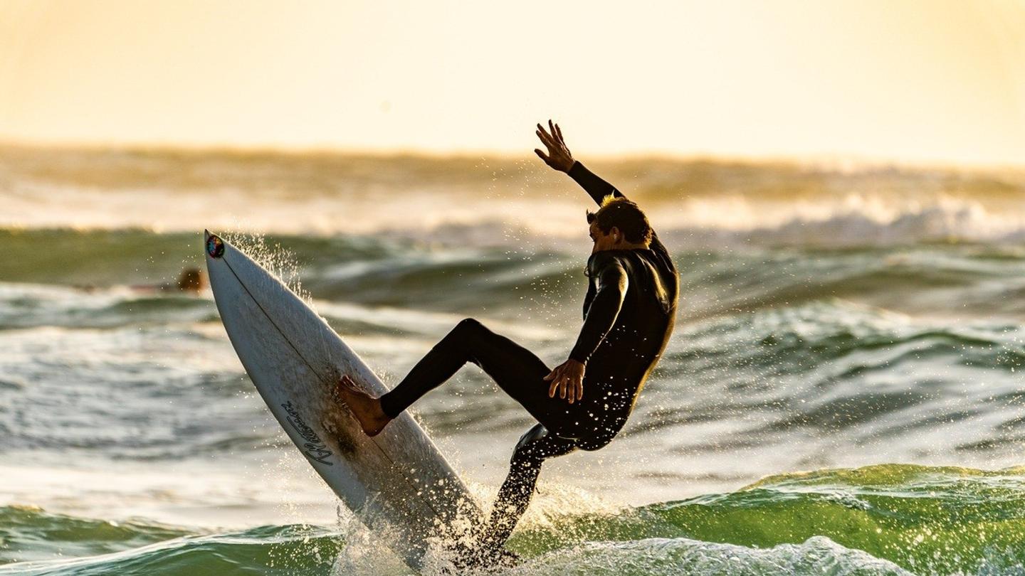 A man surfing in a wetsuit.