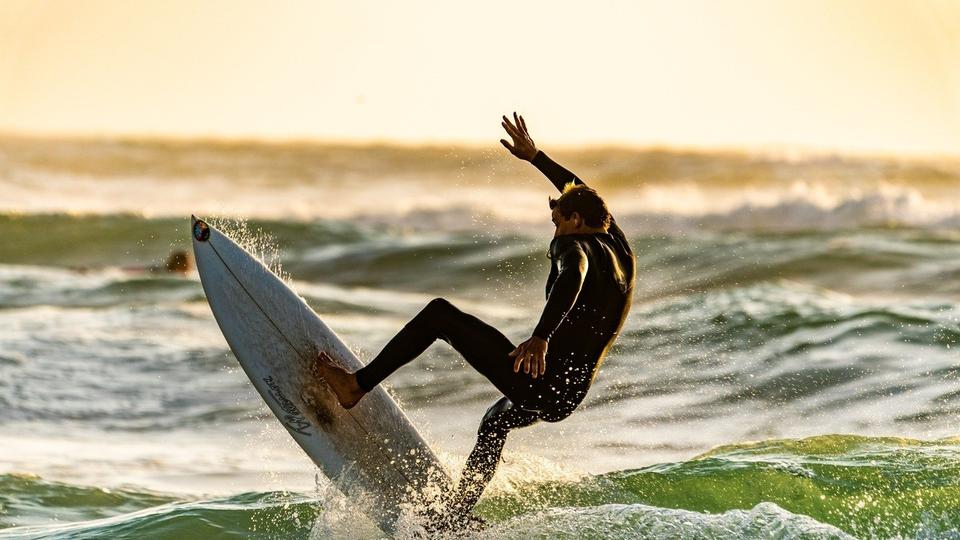 A man surfing in a wetsuit.
