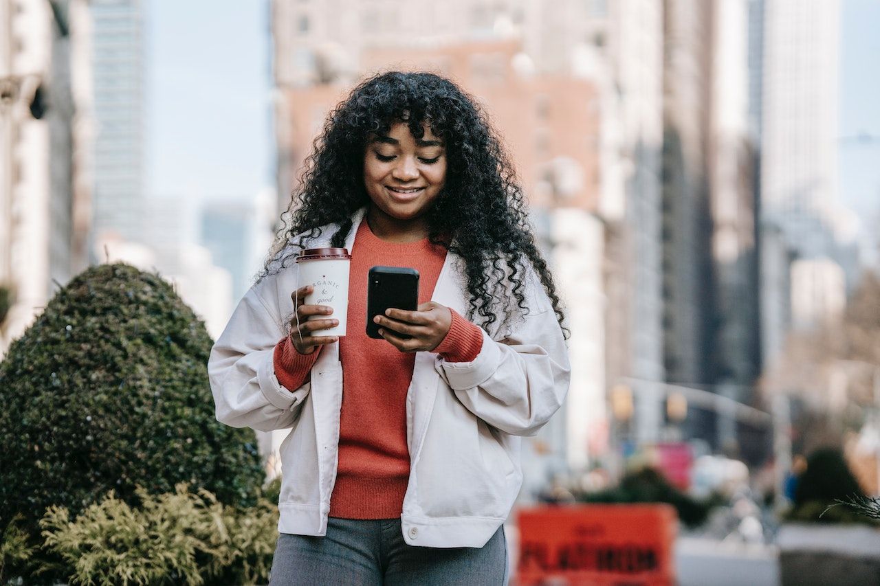 A young woman reading a pre-arrival email on her phone.