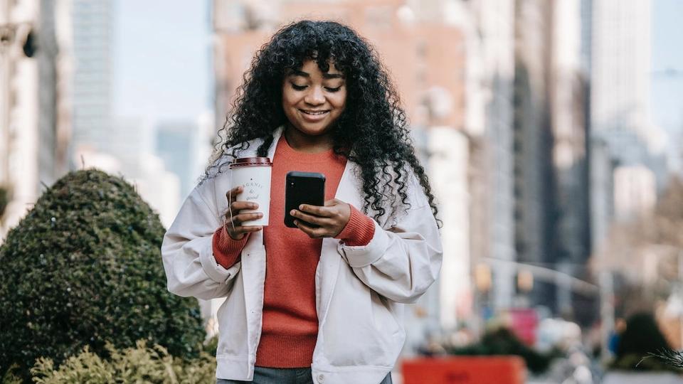 A young woman reading a pre-arrival email on her phone.