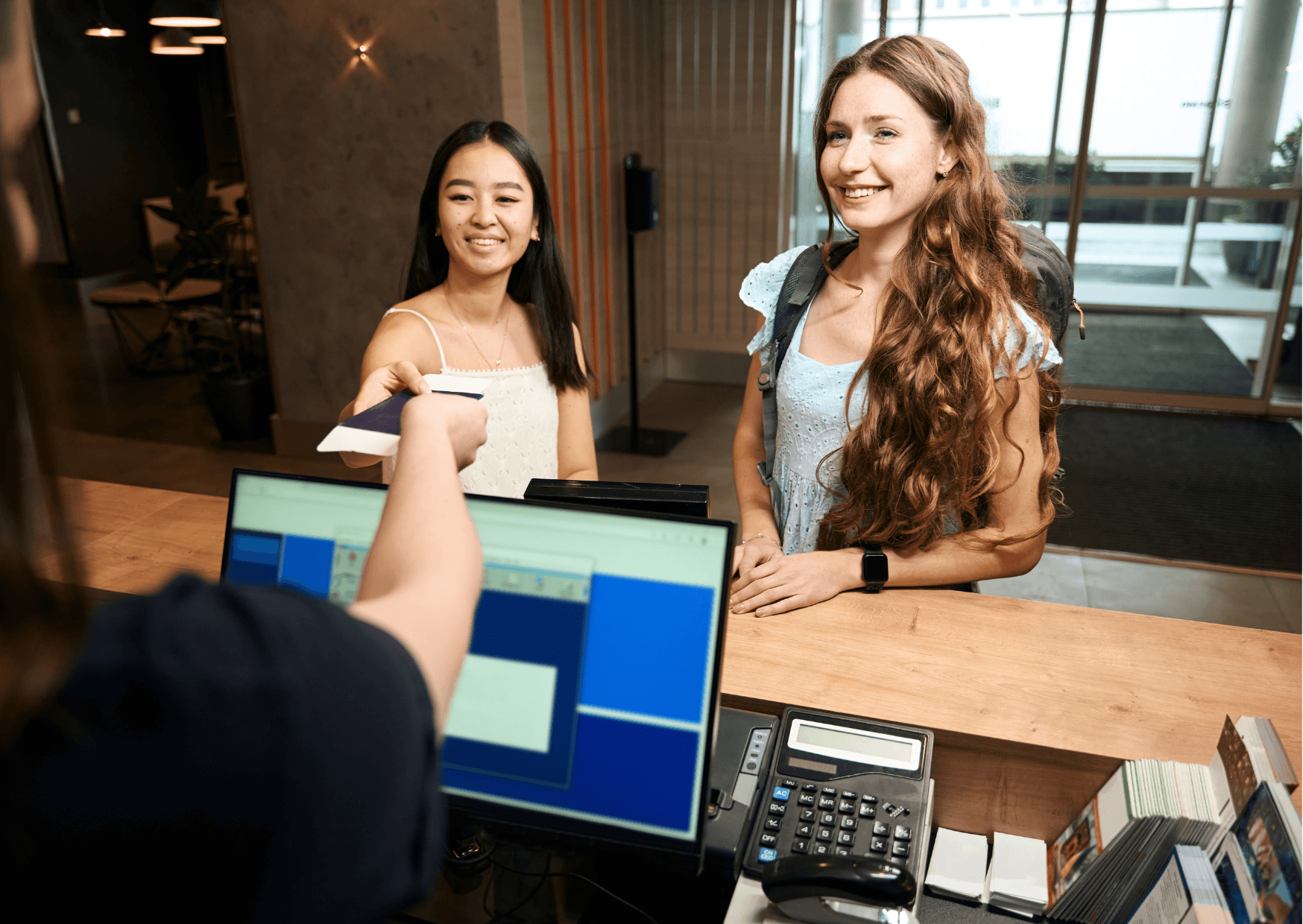 Two young women checking into a hotel.