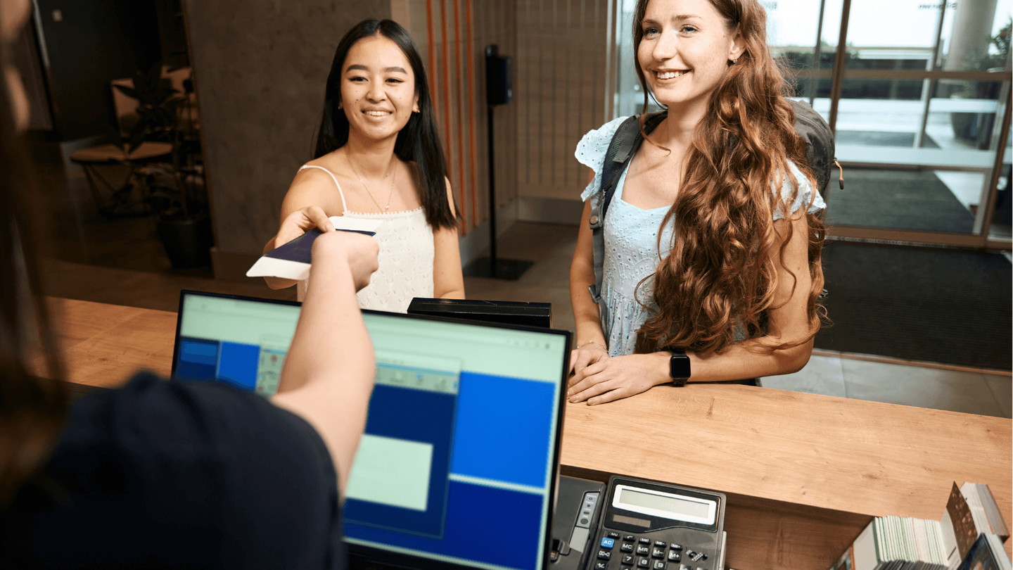 Two young women checking into a hotel.