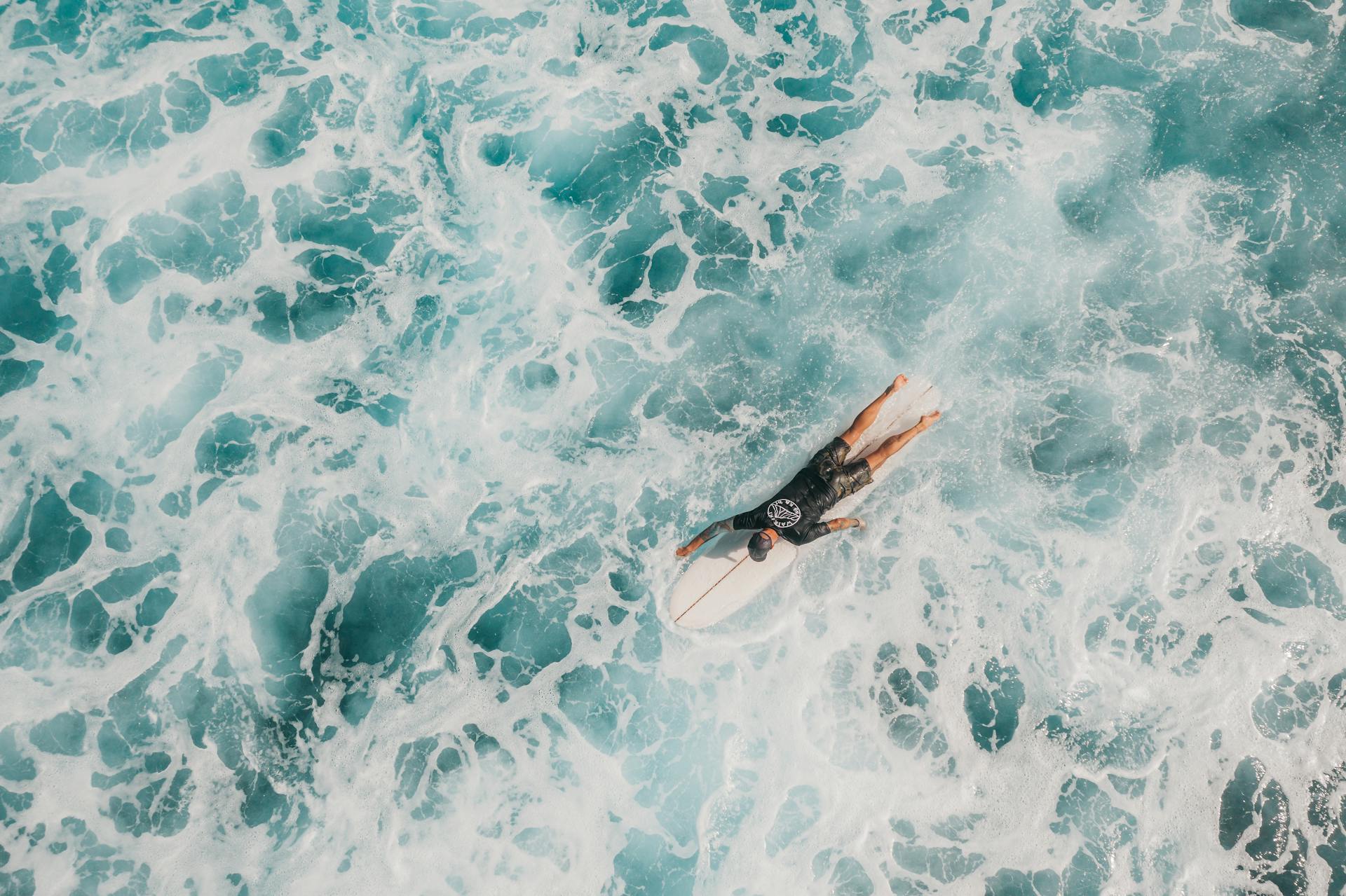 A man on a surf trip paddling through whitewash.