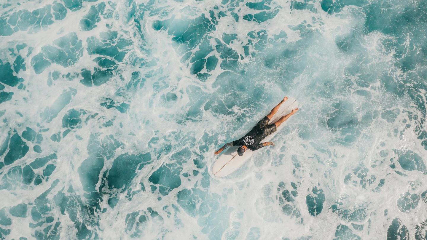 A man on a surf trip paddling through whitewash.