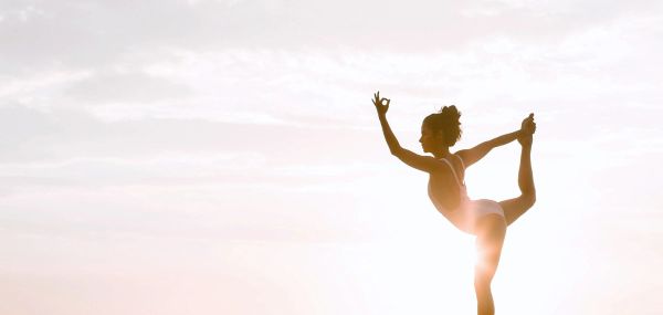 Woman doing yoga in front of the sun