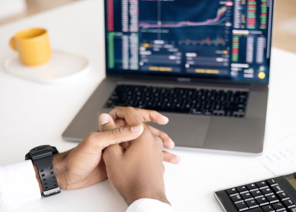 Man with his hands together looking at a laptop