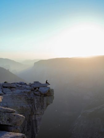 Man sitting alone on edge of cliff contemplating