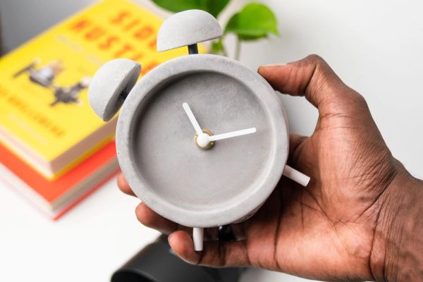 Hand holding a stone grey alarm clock