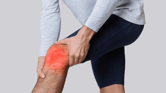 An image of a man's bent knee being grasped in pain by hands, showing joint inflammation with glowing red areas.