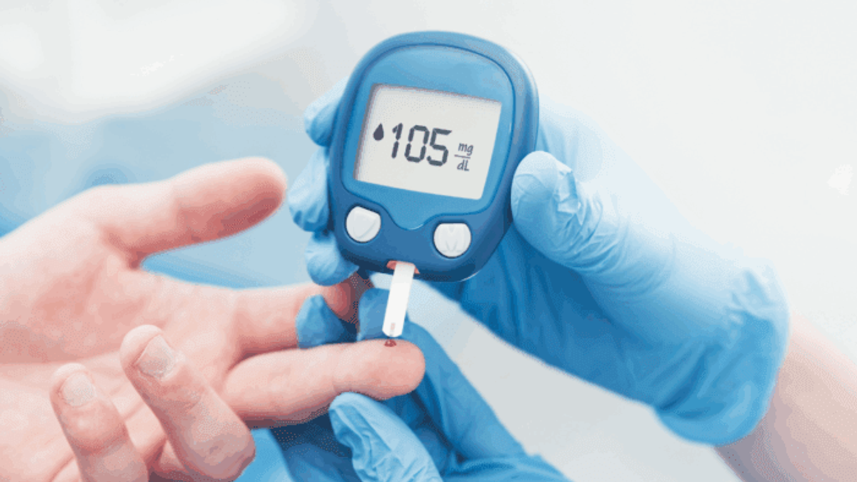 A healthcare professional wearing blue gloves checks a patient's blood glucose using a glucometer, which displays a reading of 105 mg/dL.