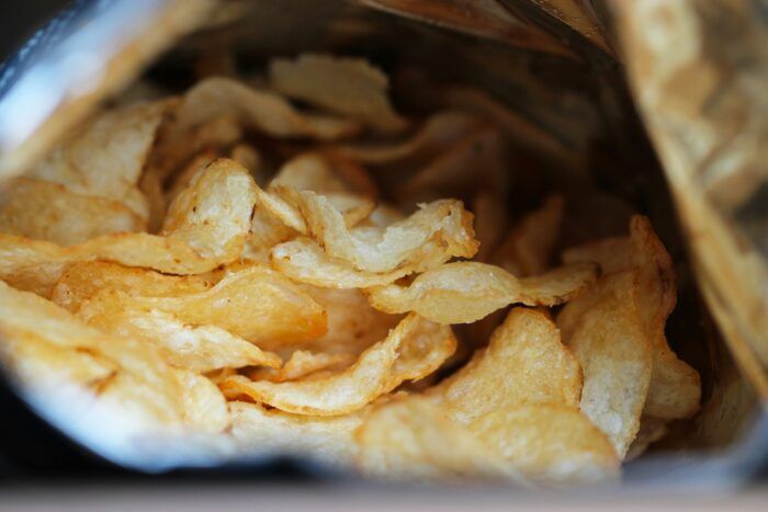 This image draws viewers into the depths of a potato chip bag, the crispy, golden chips practically begging to be eaten. The close-up shot emphasizes the texture and appeal of processed, salty snacks, highlighting the temptation and addictive quality of such foods. Perfect for discussions on snacking habits, processed foods, or the challenges of resisting junk food cravings.