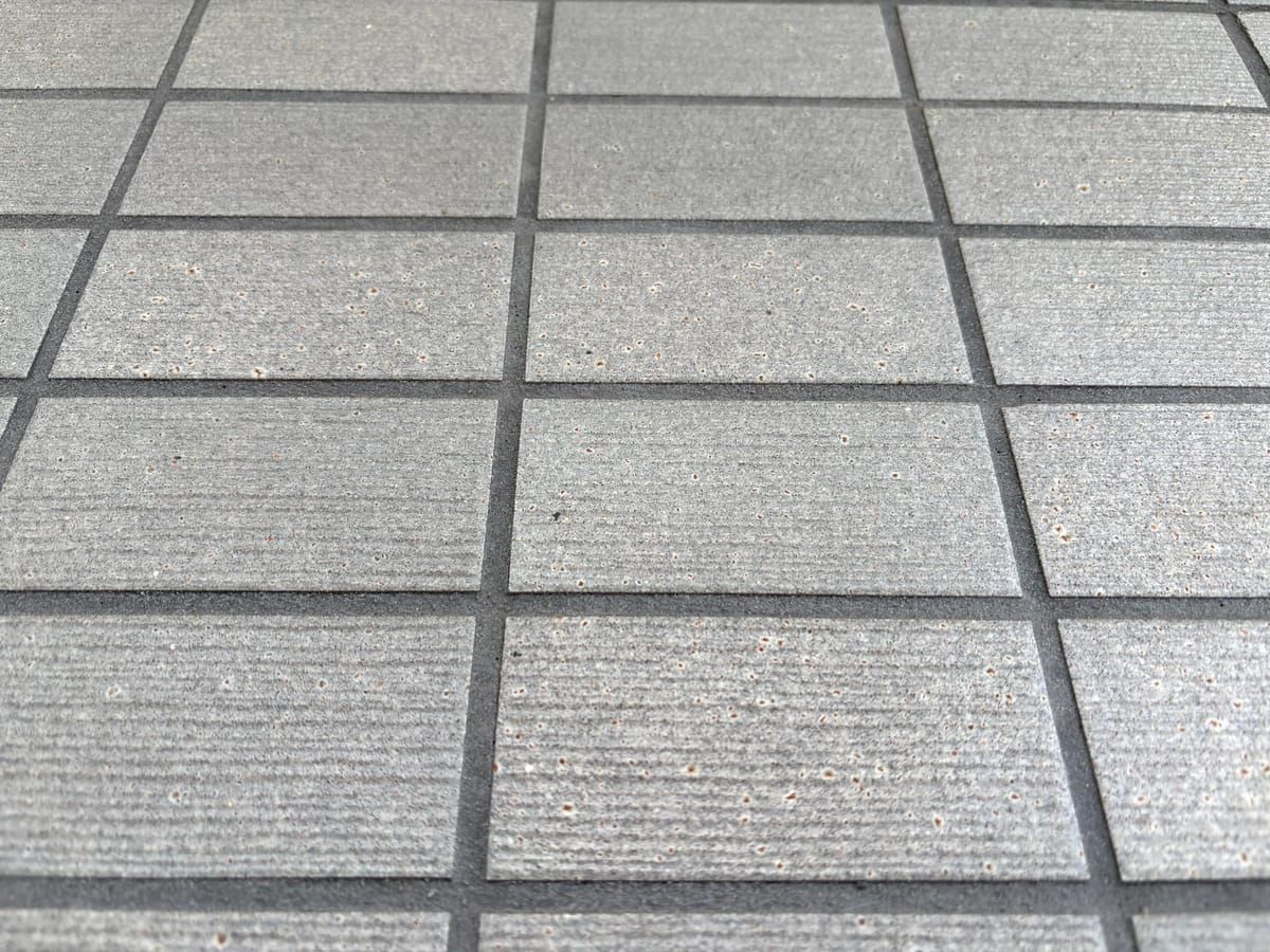 整ったグリッドで張られた白系タイル壁面