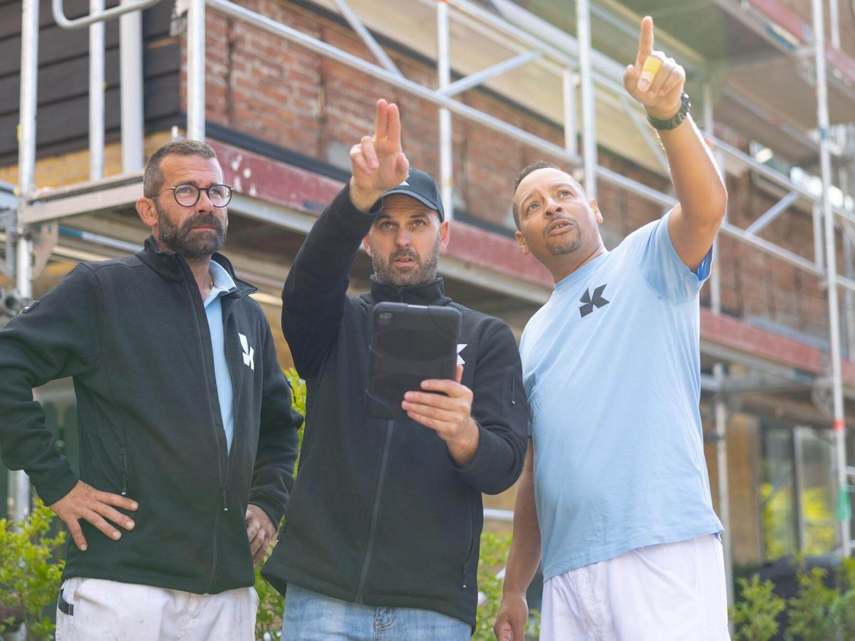 Drie medewerkers van Koestr overleggen bij een steiger
