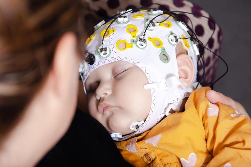 Baby asleep in EEG cap in woman's arms