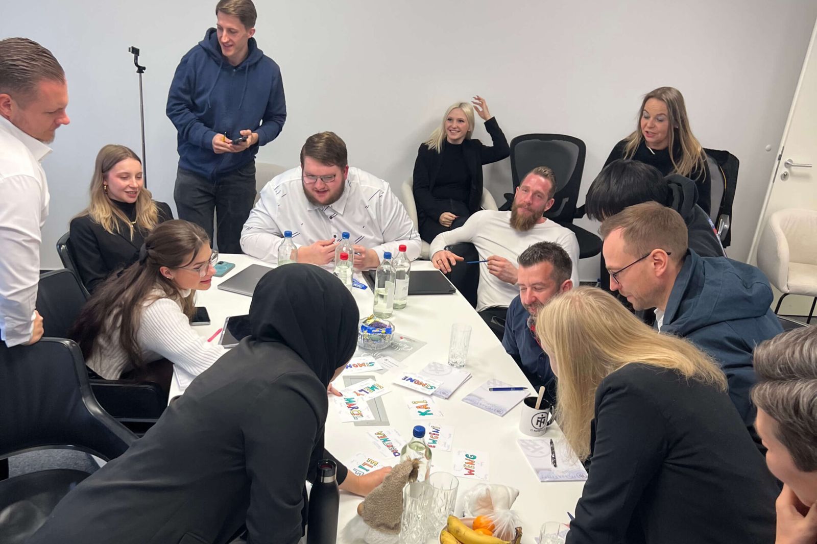 Teilnehmende eines Workshops von Shila Driesch arbeiten gemeinsam am Tisch mit Karten und Unterlagen