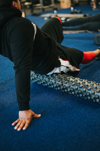 A man at the gym foam rolling his glutes