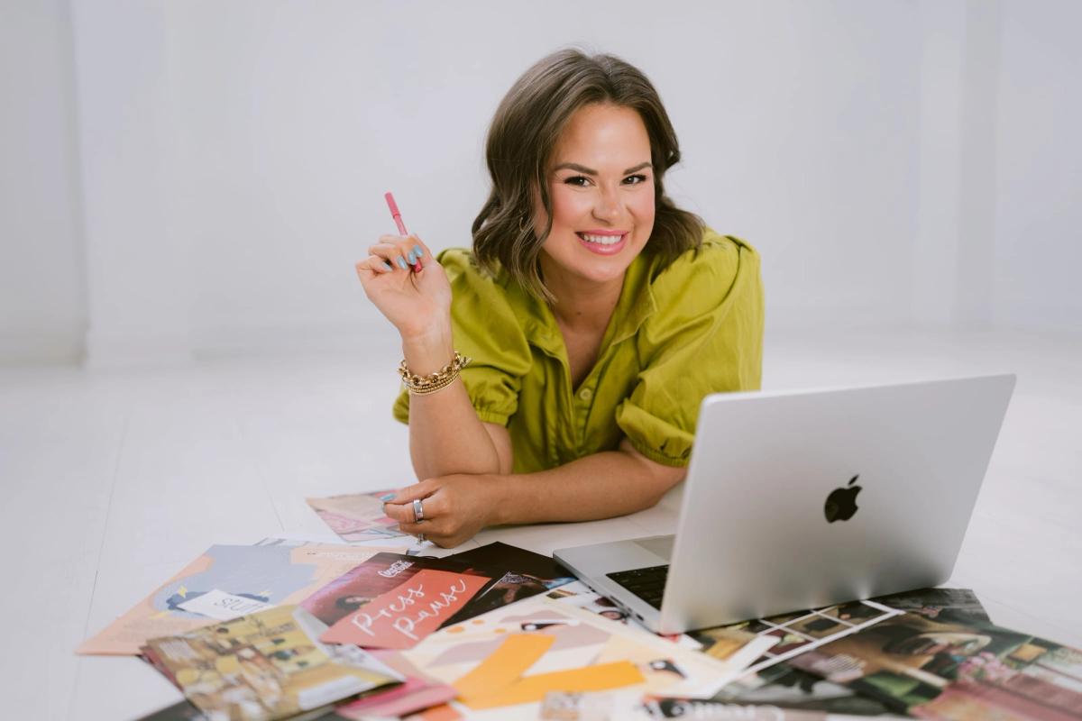 Candace lying on the floor with her laptop, surrounded by a spread of magazine cutouts