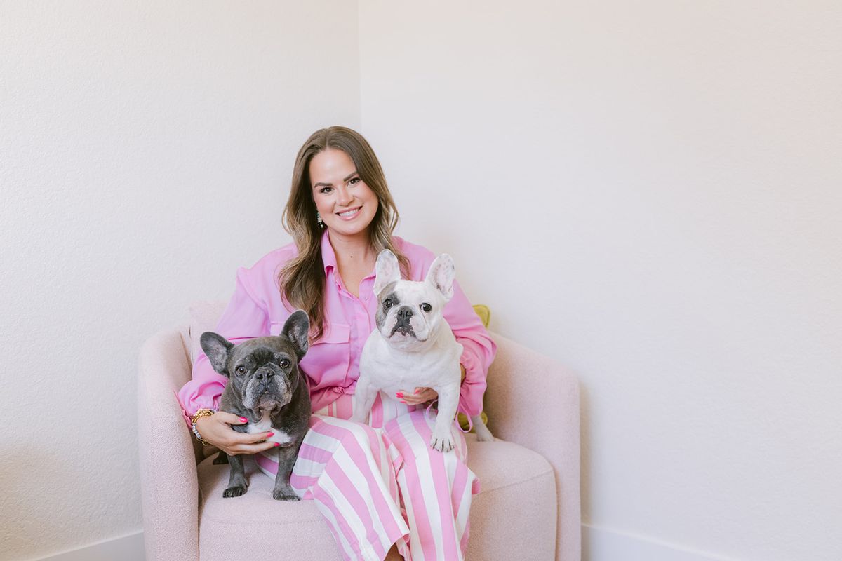 Candace on a pink armchair with her two French bulldogs