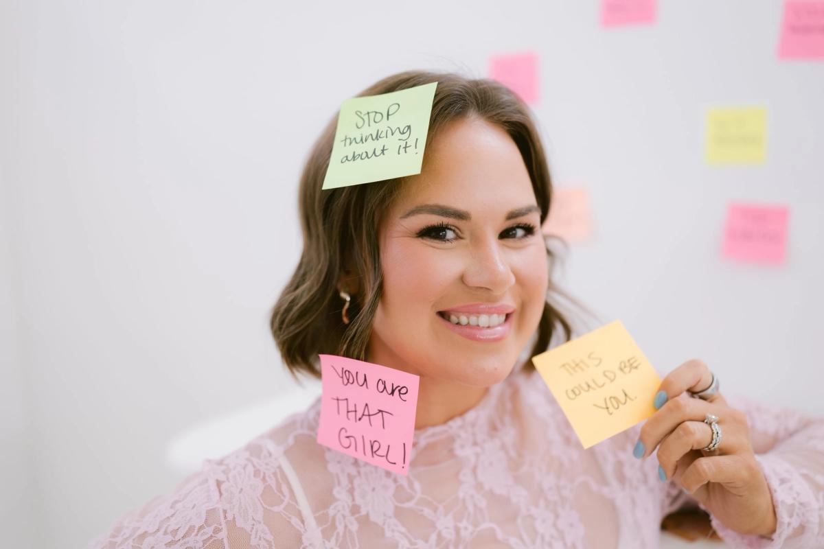 Candace smiling, sticky notes with handwritten notes stuck to her face and in her hand