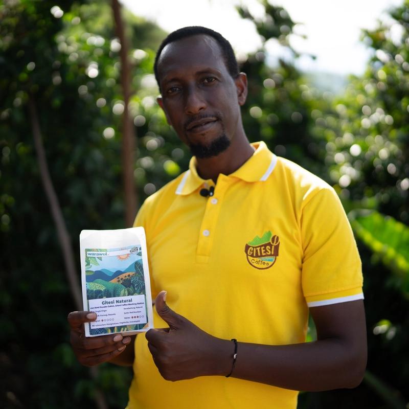 Aimé hält eine Tüte mit geröstetem Warawul-Kaffee in der Hand.