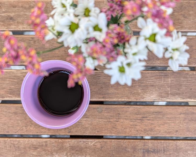 Tasse Filterkaffee auf Holztisch mit Blumen