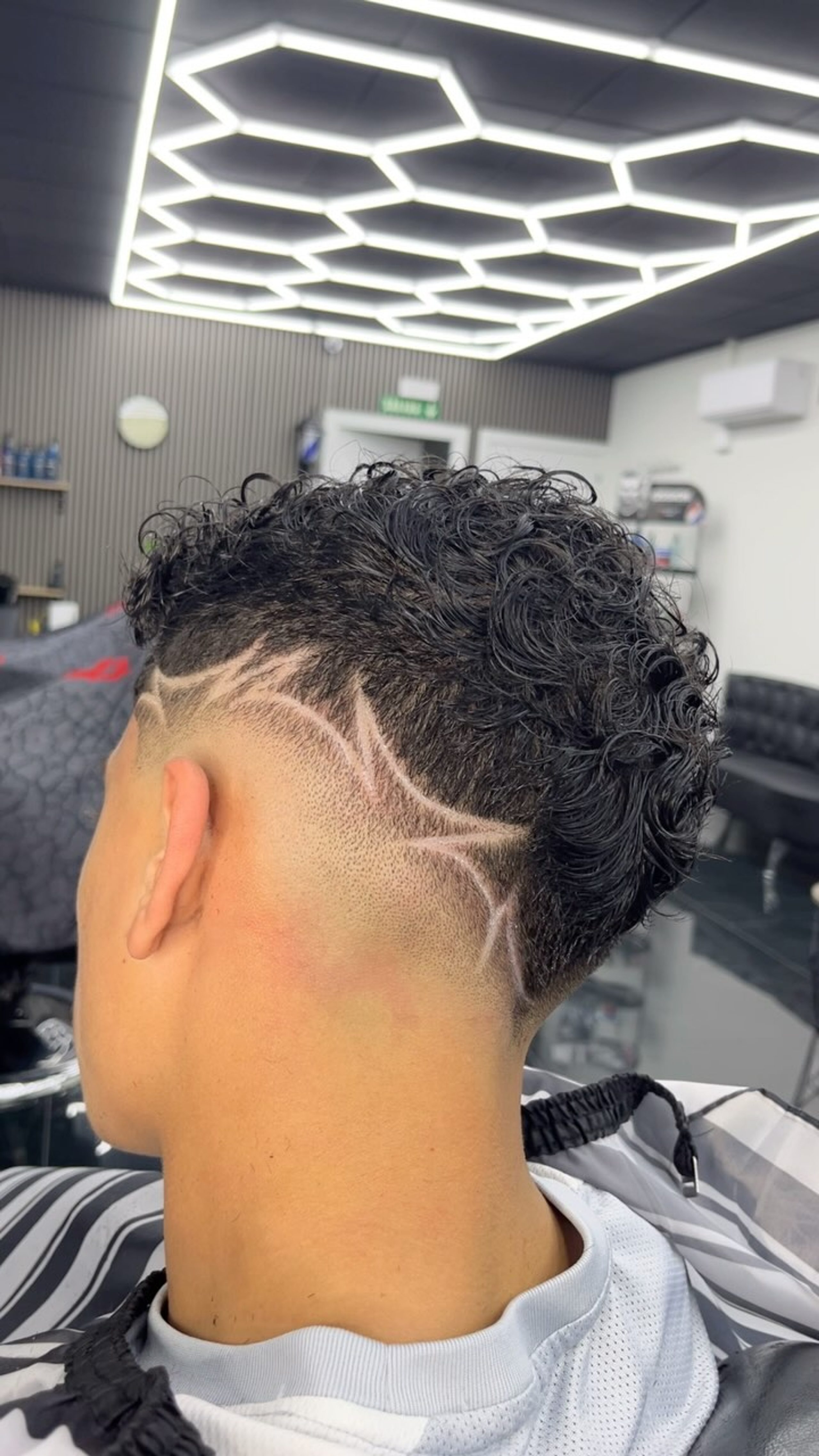 Línea rasurada dibujada sobre el pelo rizado del lateral
