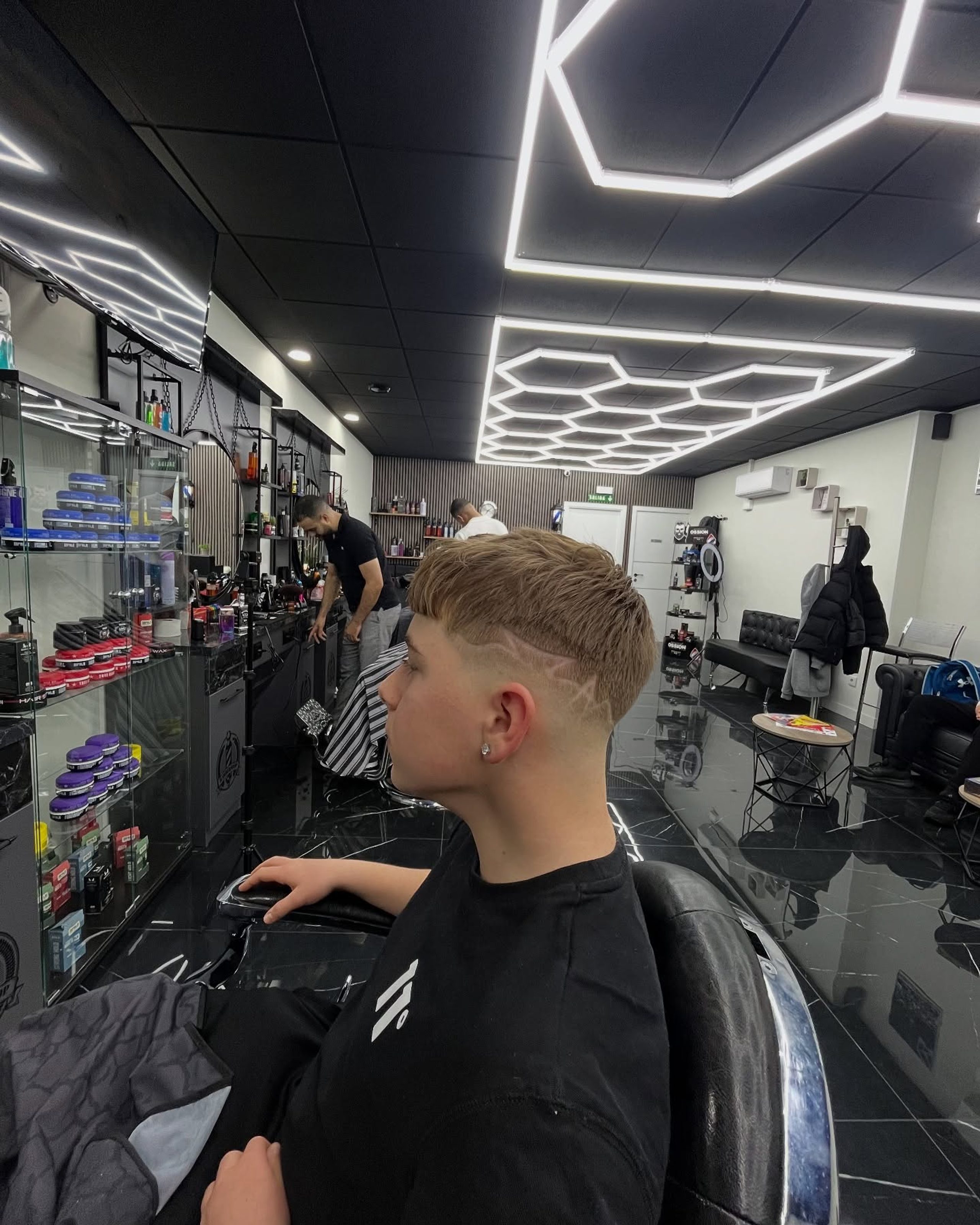Cliente en el sillón durante el corte, con la barbería al fondo