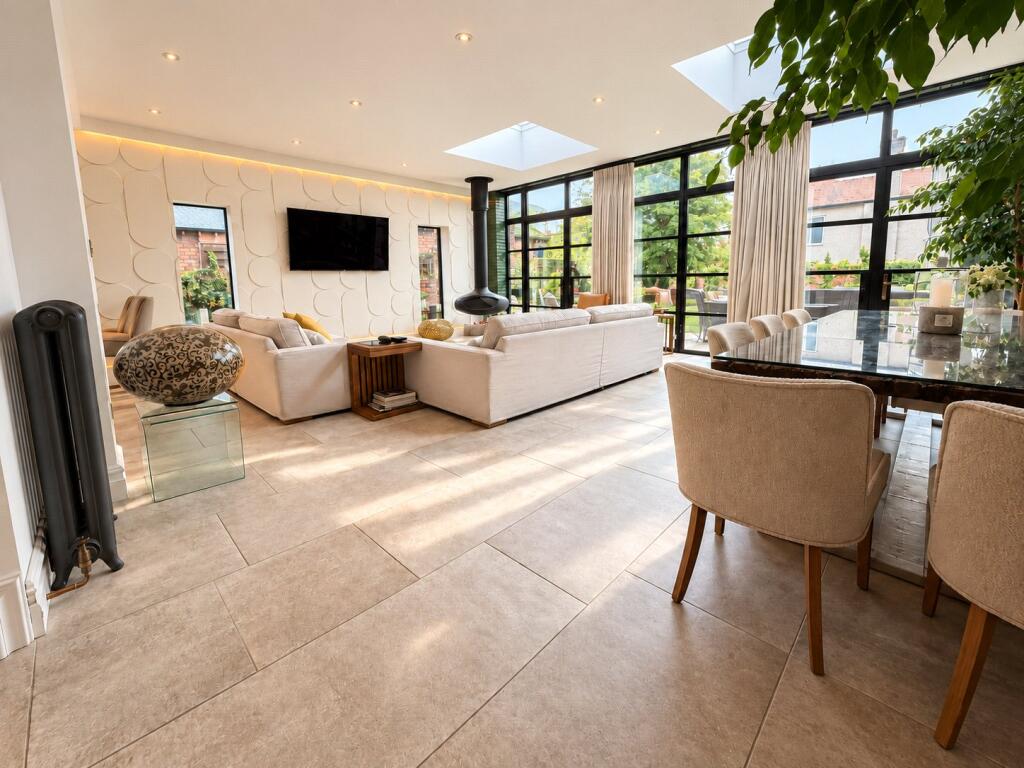 Open-plan living space with steel-look aluminium doors along the garden wall