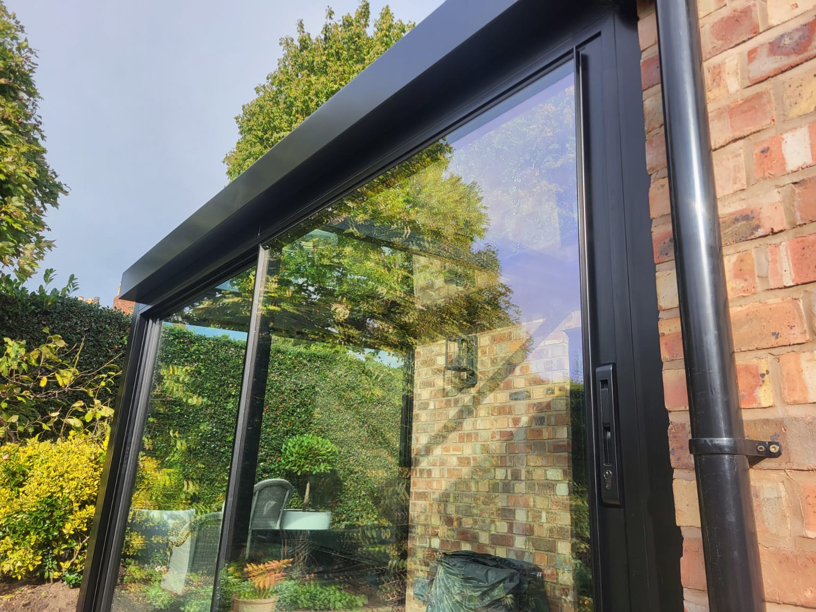 Detail of black aluminium head, sliding door handle and glass on a Bowdon glass box