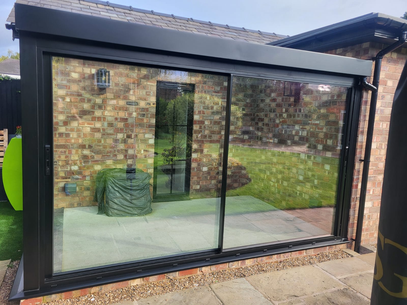 Wide two-pane Cortizo sliding doors in black aluminium on a glass box, Bowdon