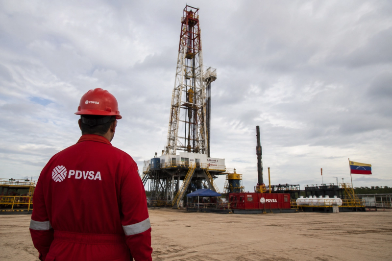 Trabajador petrolero frente a una instalación de producción de petróleo en Venezuela
