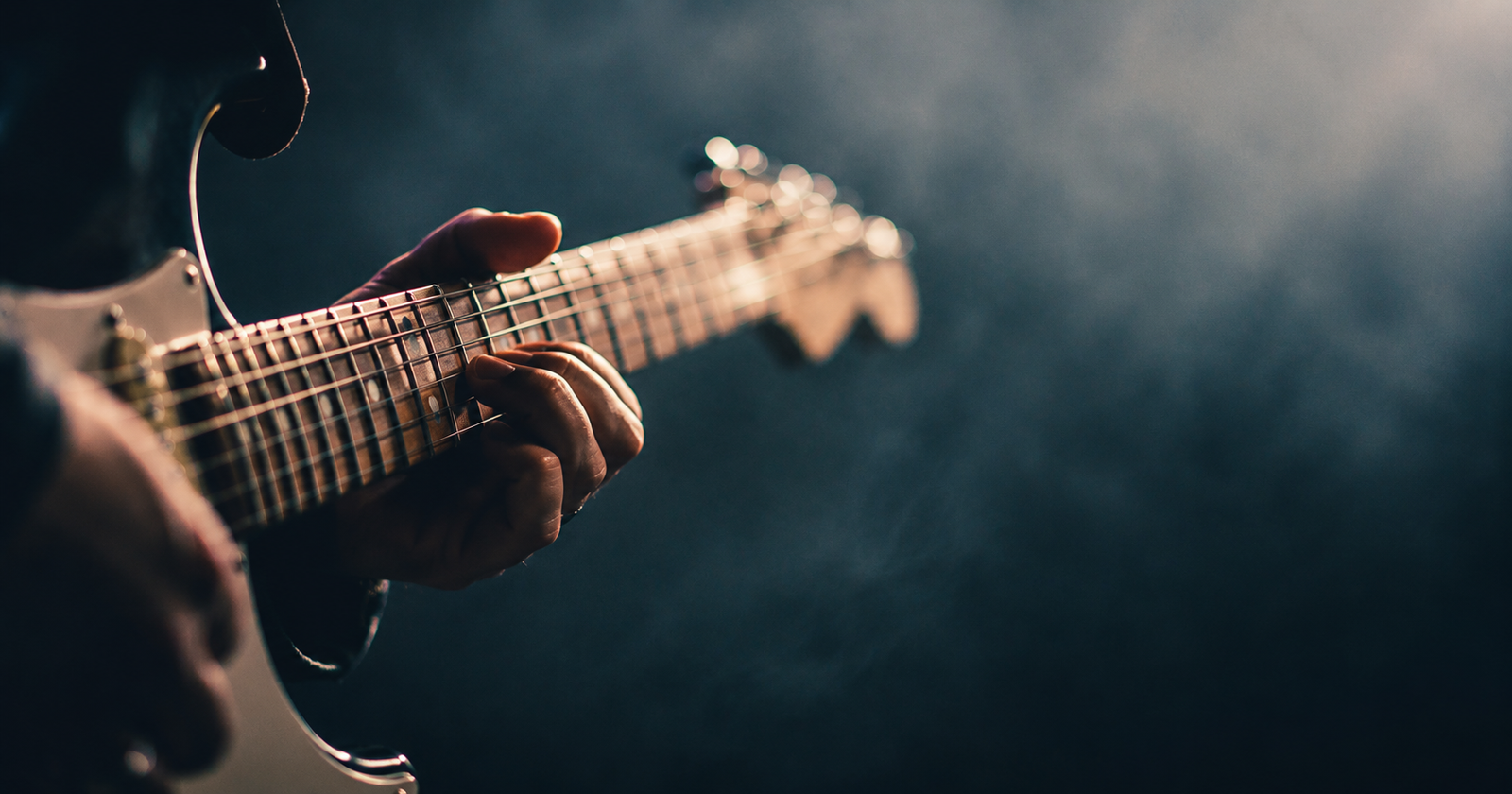 A hand caught mid-riff on an electric guitar neck