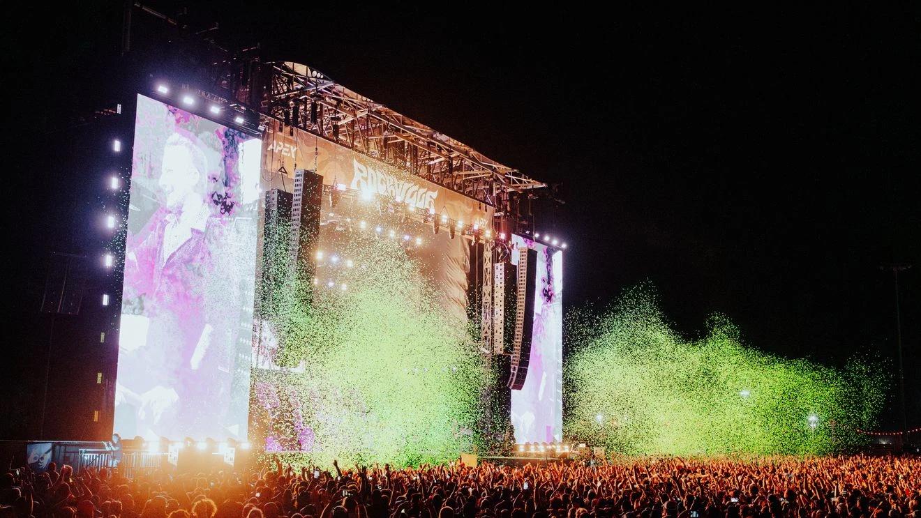 Large crowd at an outdoor rock festival main stage at night