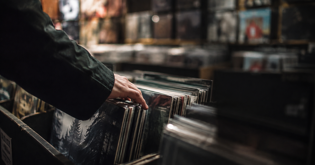 Hands flipping through vinyl records in a shop.