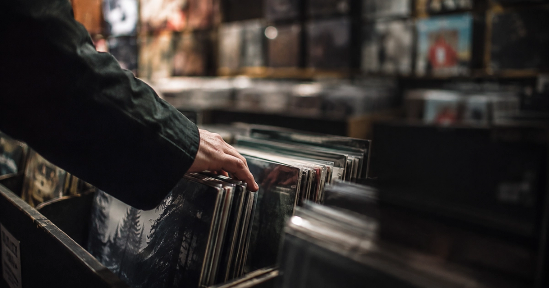 Hands flipping through vinyl records in a shop.