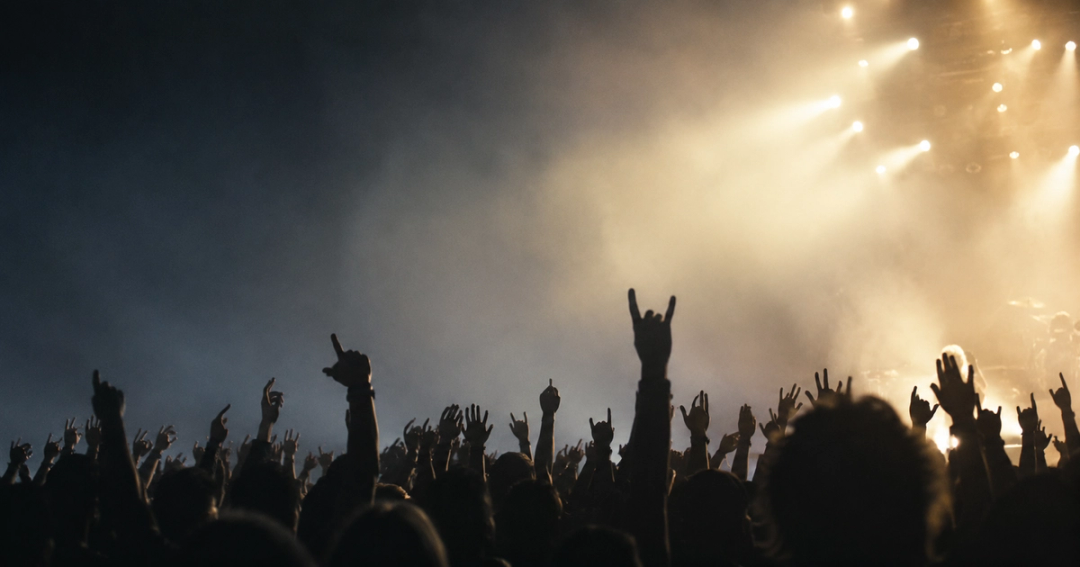 Raised hands silhouetted against stage light at a rock concert