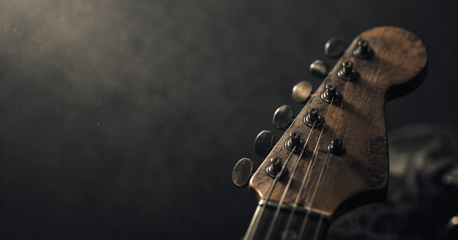 A worn electric guitar headstock in low light