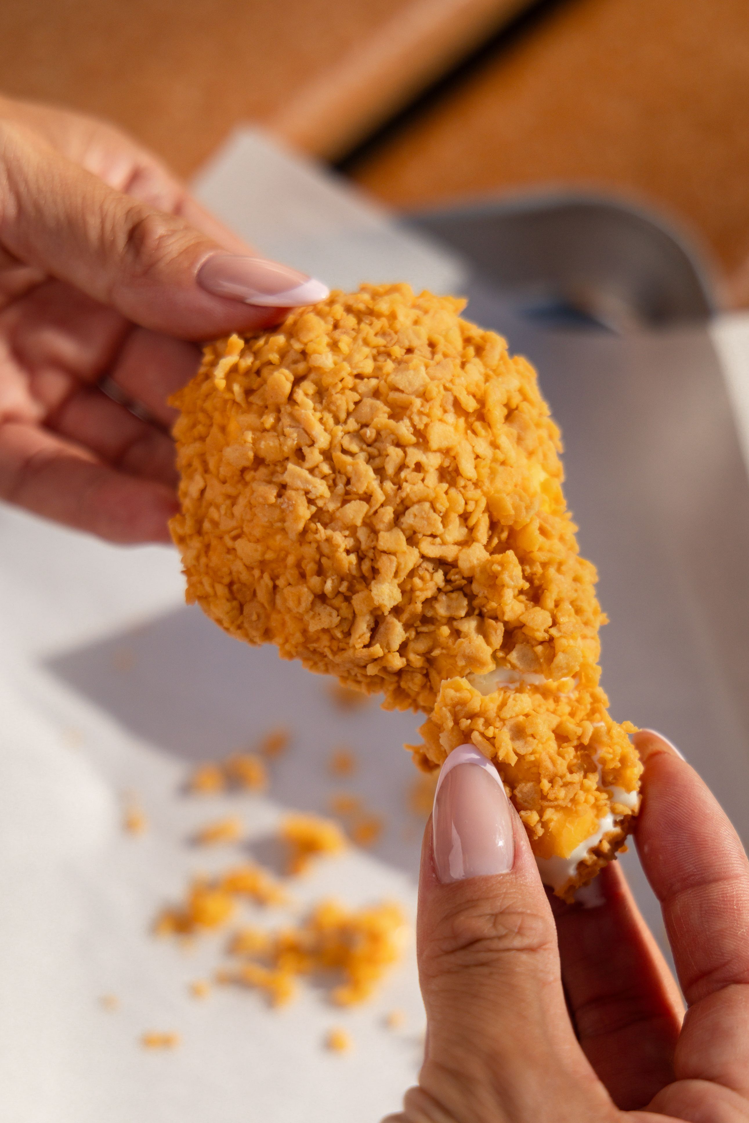 Close-up of hands holding a crispy coated ice cream bar