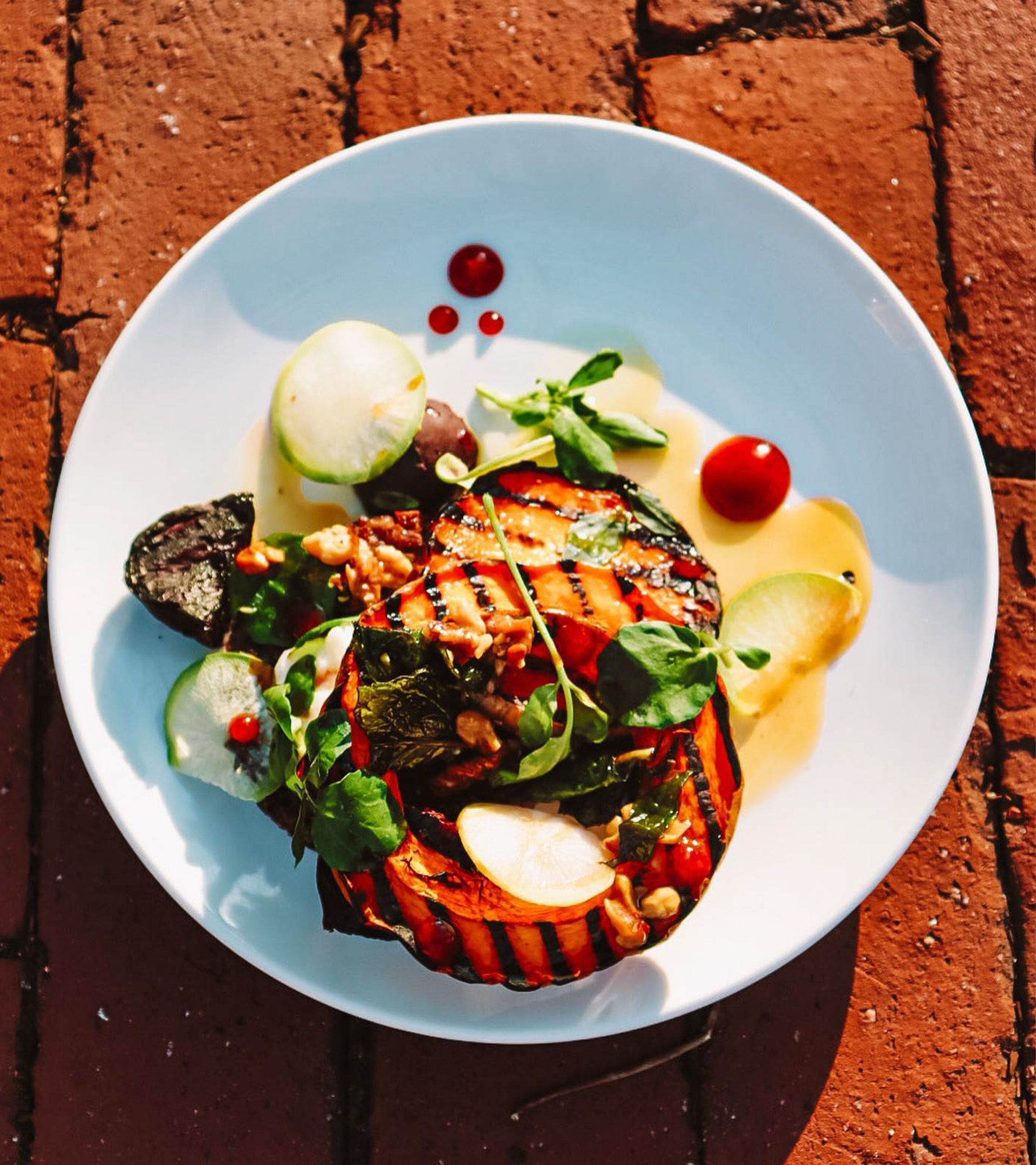 Forage plate: charred vegetables with cherry tomatoes, greens, overhead white bowl