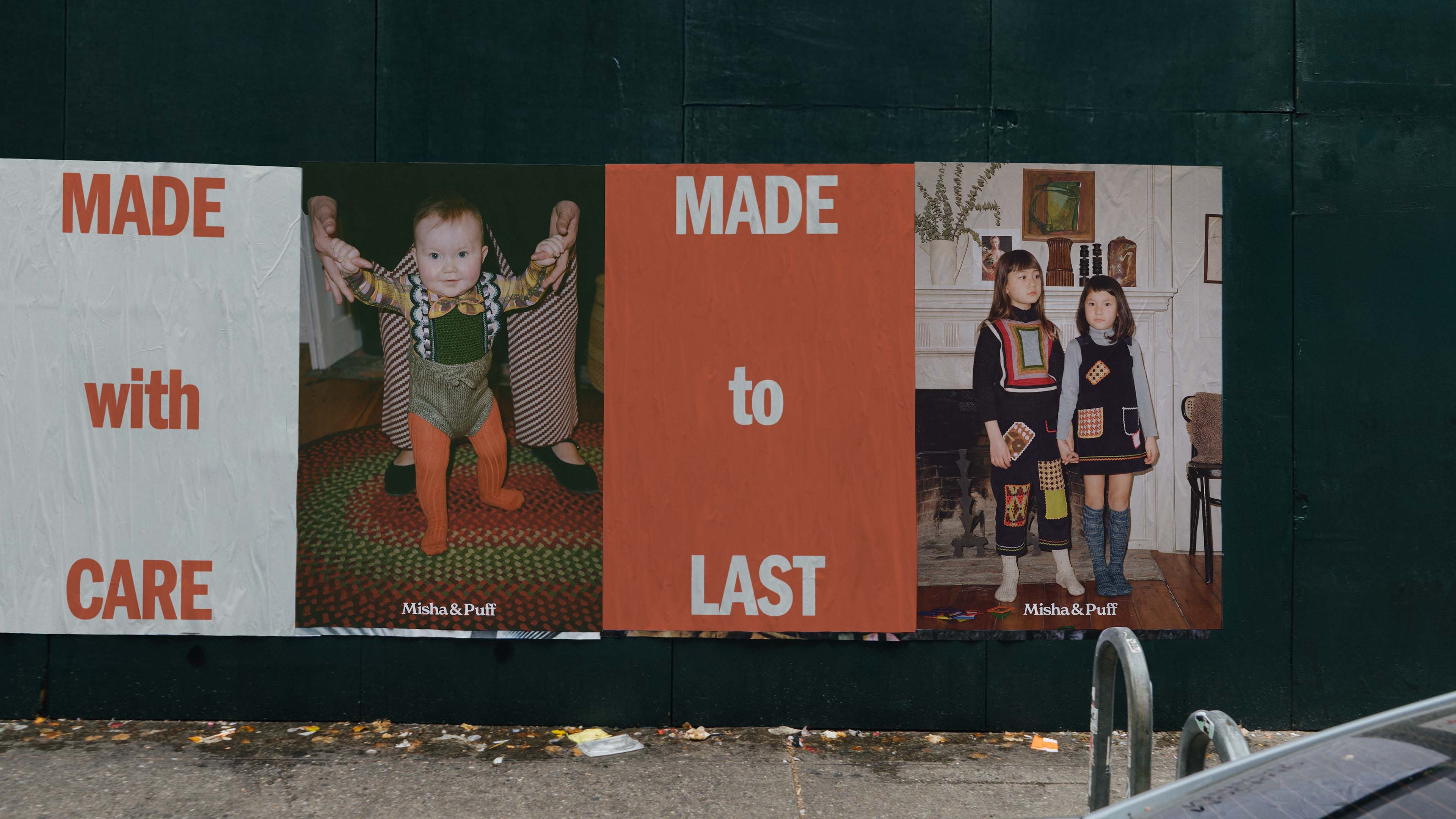 Misha & Puff wheat-paste campaign on a dark construction wall: "Made with Care. Made to Last." with child portrait panels.
