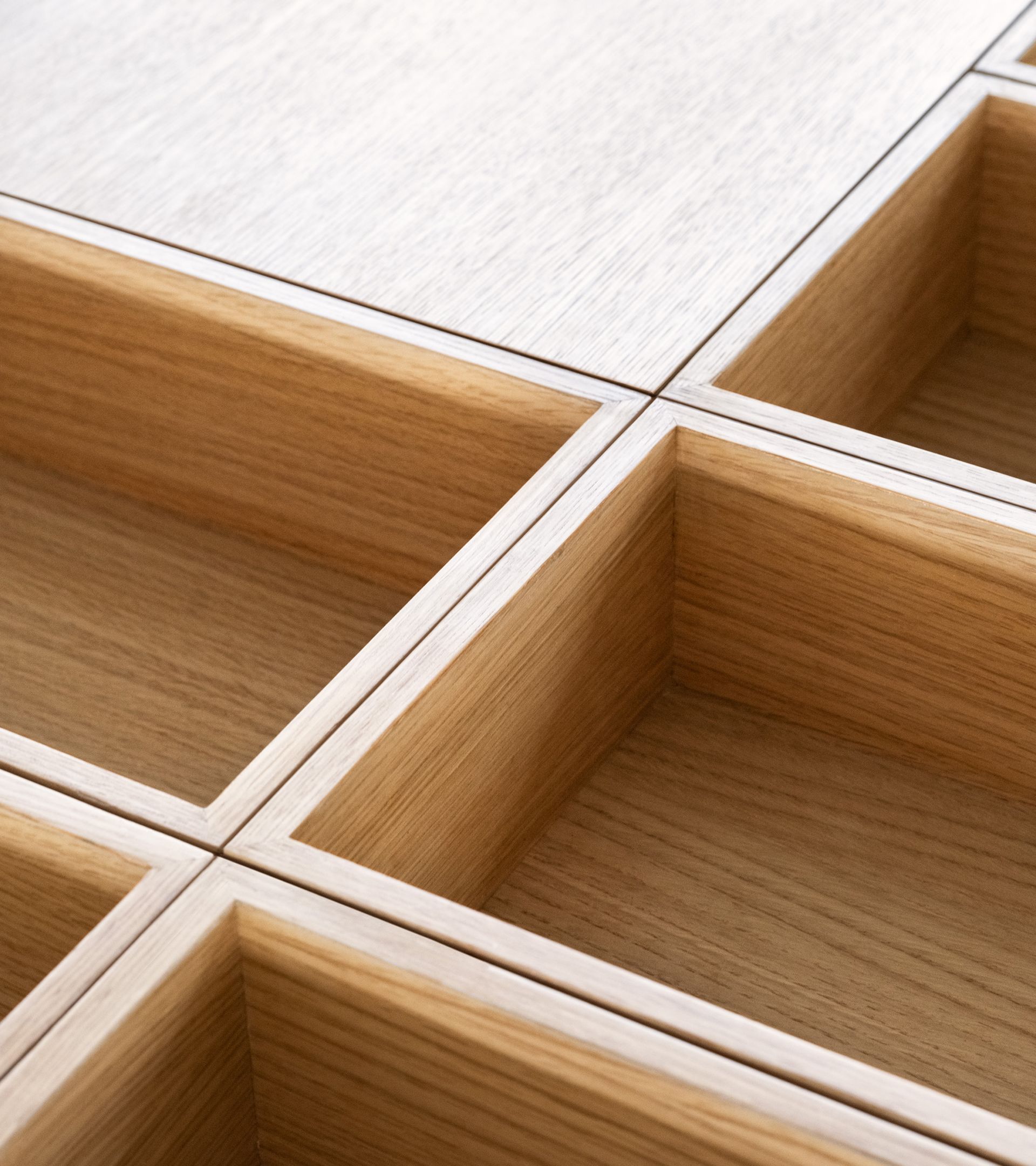 Natural oak display furniture macro: four open-compartment boxes joined at right angles, joinery detail