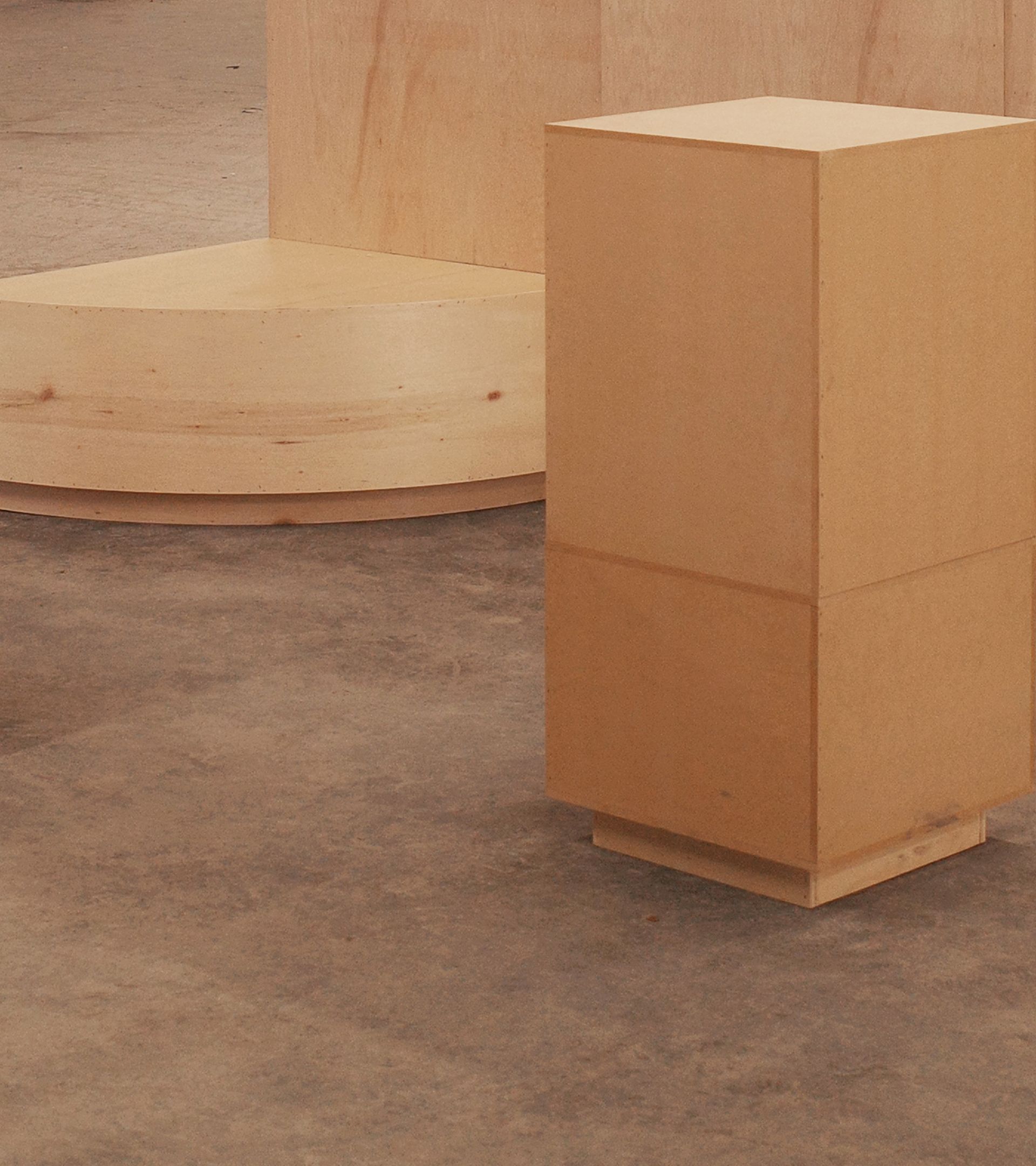 Construction detail: birch plywood pedestal and curved platform base on concrete floor, raw finish