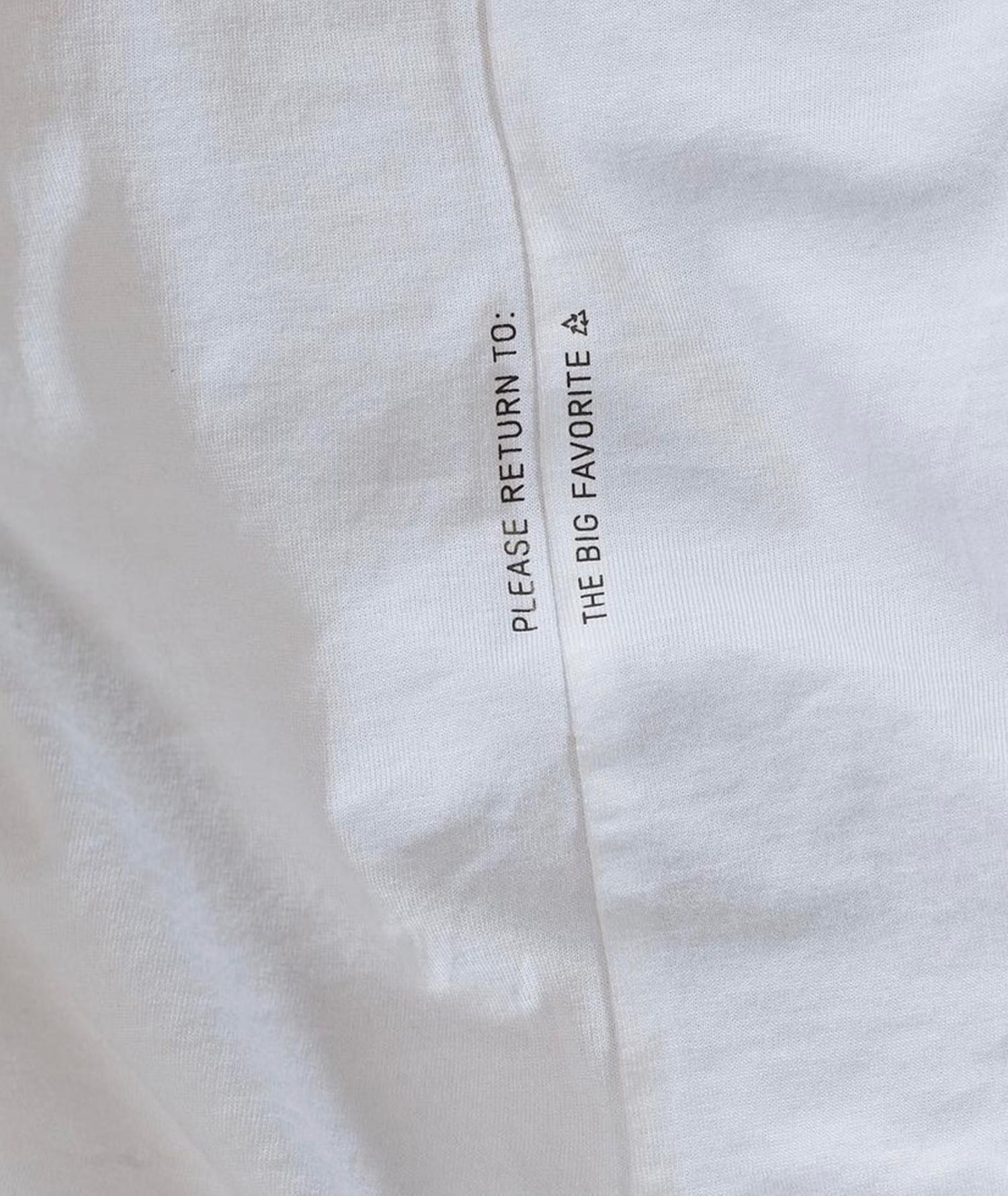 'PLEASE RETURN TO: / THE BIG FAVORITE ♻' printed on white garment interior seam — recyclable garment branding