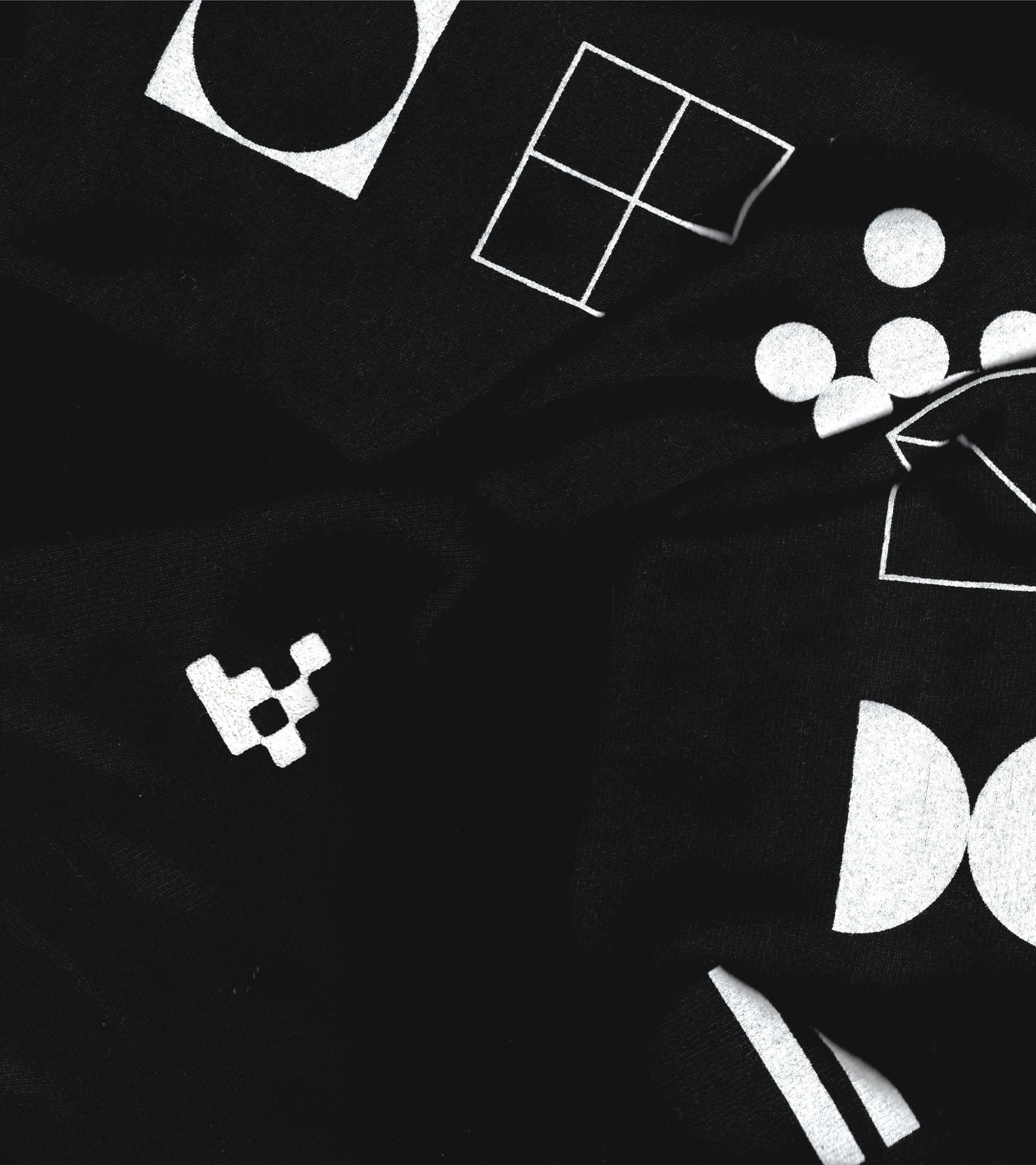 Variant merch fabric close-up: scattered white brand mark icons; V logo, quarter-circle, dot cluster; on black