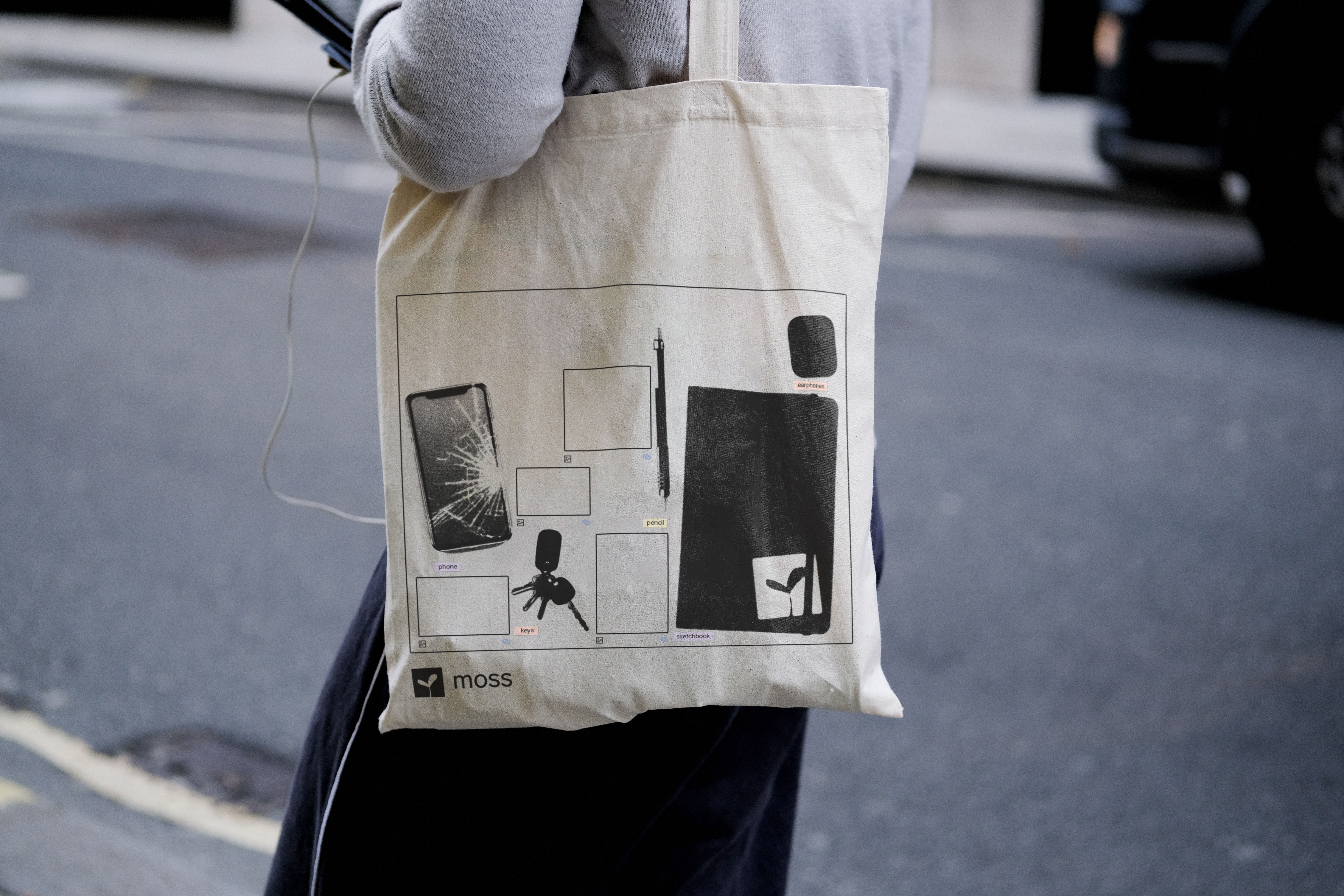 Canvas tote on street: Moss app canvas UI printed with labeled items, 'Moss' logotype lower left