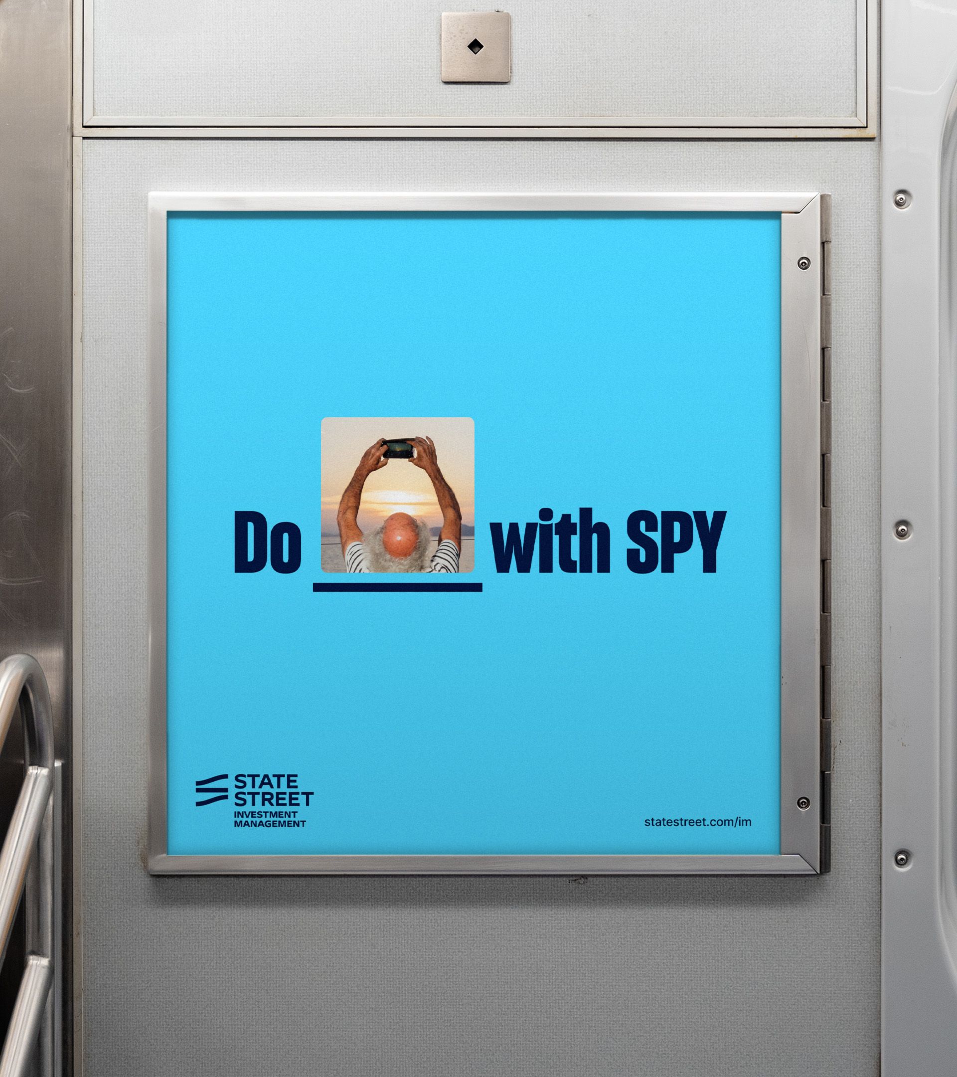 Subway ad: "Do [photo] with SPY" on sky blue; photo of man shooting a sunset fills the blank, logo below