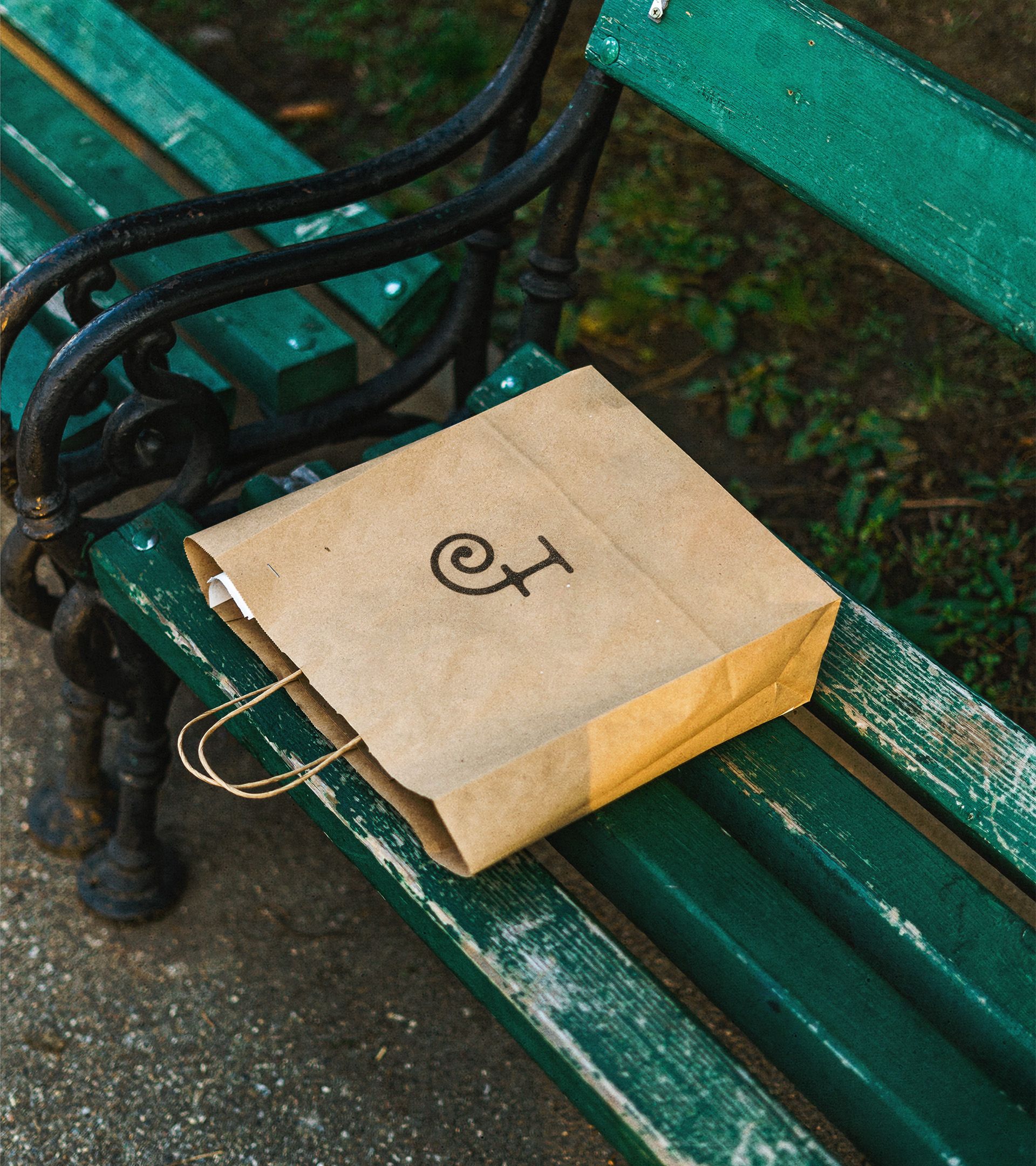 Forage branded kraft bag with "f" logo on green park bench