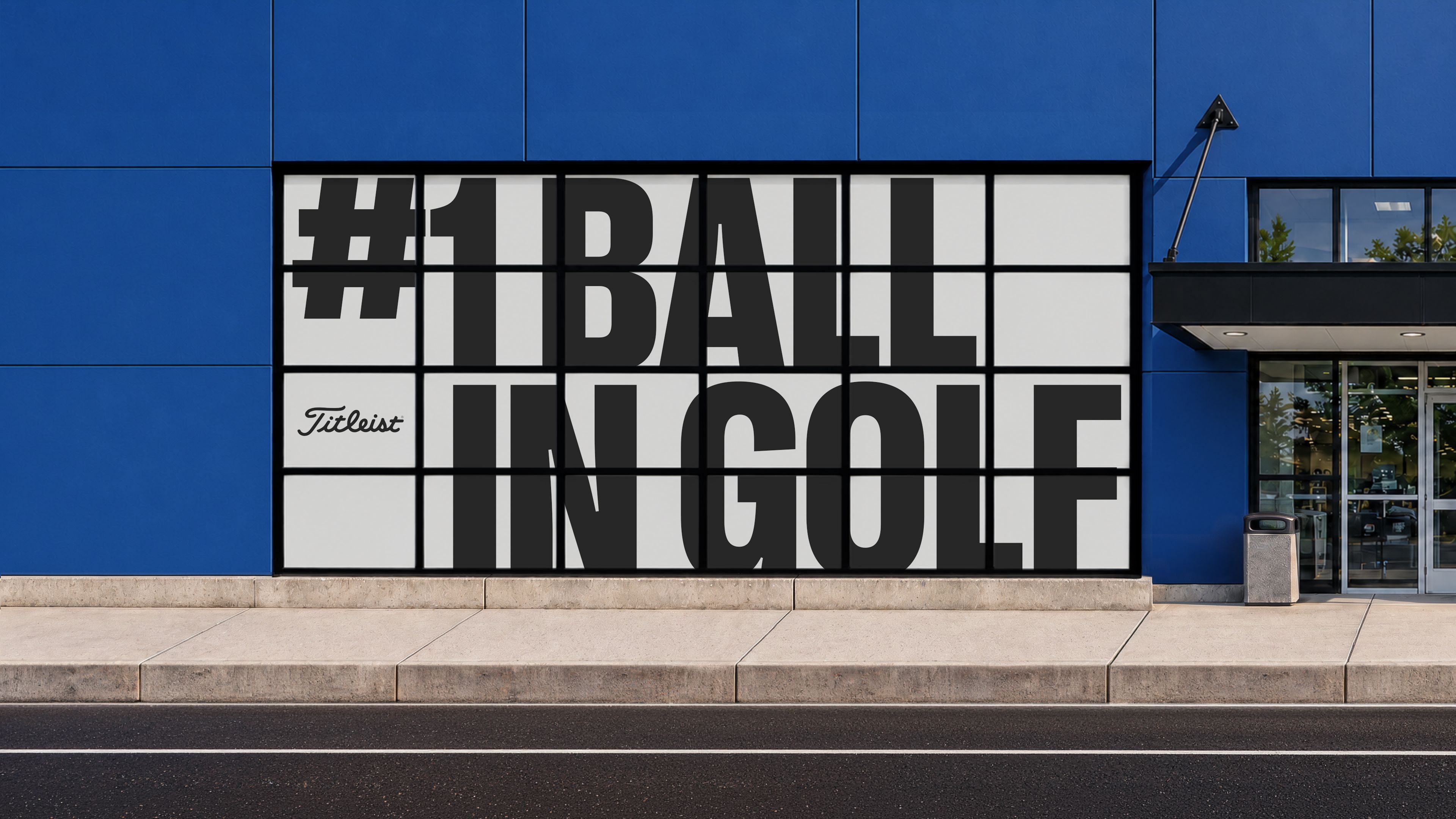 Blue retail storefront with a gridded window filled by giant black lettering reading “#1 Ball in Golf” and a small Titleist logo.