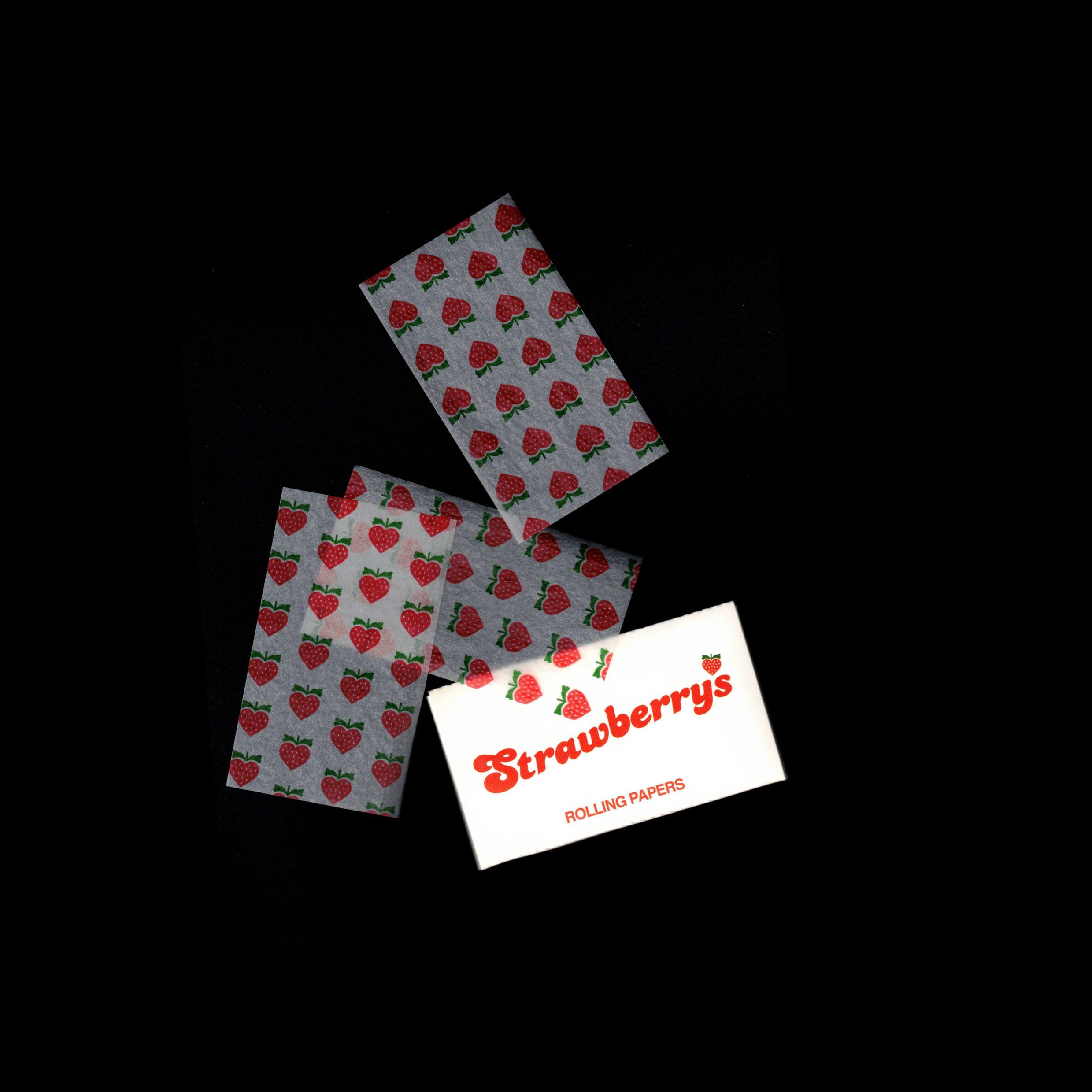 Scanned Red Rocket "Strawberrys Rolling Papers" booklet with loose papers — strawberry-heart pattern, red type on white label